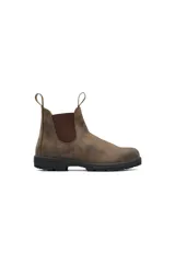 Botas Chelsea Blundstone modelo 585, confeccionadas en gamuza marrón repelente al agua. Presentan paneles laterales elásticos en color marrón oscuro, tiradores en la parte superior y suela de goma antideslizante con entresuela acolchada.
