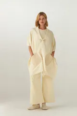 Chal de lana fina sin teñir con diseño de cuadros sutiles, cierre frontal con alamar y bolsillos de cuero metalizado. Presenta terminaciones con flecos en el ruedo y un calce estructurado en los hombros.