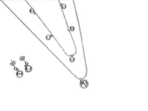 Set de collar doble y caravanas colgantes de acero plateado con dijes de bolitas.