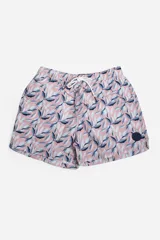 Short de baño celeste con estampado de hojas pequeñas en tonos verdes y blancos. Cuenta con cintura elástica con cordón ajustable, bolsillos laterales y un parche circular con logo en la parte inferior.