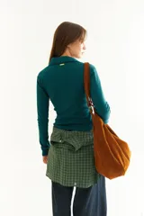 Top de manga larga color verde petróleo, con cuello polo y escote en V pronunciado. Presenta recortes diagonales en el frente y un pequeño bordado en el puño.