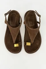 Sandalias de gamuza color tostado, con tira de dedo, hebilla ajustable en el talón y detalle metálico dorado.