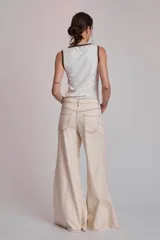Pantalón de jean color crudo, corte palazzo con godets y costuras a contratono.