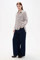 Camisa de viscosa con estampado de rayas verticales en tonos marrón y blanco, de corte holgado, cuello camisero, manga larga y bolsillos frontales.