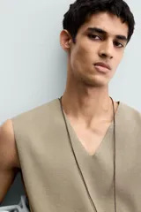 Chaleco de punto color beige claro, con cuello en V y corte relajado sin mangas.
