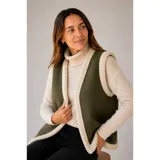 Chaleco estilo gamulán en color verde militar, con forro interior y bordes de corderito sintético en tono crema. Presenta un diseño sin mangas, ideal para usar sobre prendas de abrigo.