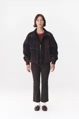 Campera de denim azul con corte oversized, cierre frontal y cuello de piel sintética marrón desmontable. Presenta detalles de volados en el frente, puños elásticos y logo bordado en el pecho.