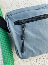 Bandolera azul de nylon con correa negra ajustable.