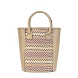 Matera color beige con diseño geométrico en tonos naranja, marrón y negro. Confeccionada en símil cuero y telar tejido, con división interior y asas cortas.