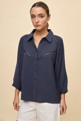 Camisa negra de calce relajado, con mangas 3/4, cuello clásico y cierre frontal con botones. Presenta detalles calados en la parte superior.