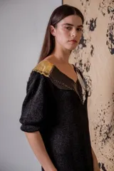 Vestido corto negro de tejido de punto con cuello en V, mangas 3/4, flecos en el ruedo y apliques de cuero en escote y hombros.