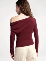 Blusa negra de manga larga con diseño asimétrico en el escote, dejando un hombro al descubierto. Presenta un corte ajustado con detalle de frunces laterales que crean un efecto drapeado en el torso.