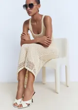 Vestido midi de crochet color beige, sin mangas, con tirantes anchos y cuello escotado. Diseño recto con forro interior.