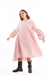 Vestido midi de algodón color rosado, con silueta amplia y mangas largas voluminosas con detalle de tablas. Presenta cuello redondo y diseño minimalista.