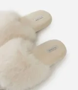 Pantufla abierta color blanco, con plataforma baja y recubierta de piel sintética.