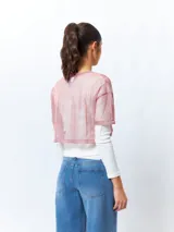 Top cropped de manga corta, color rosado, de tejido símil transparente con sutil brillo de fibras metálicas.