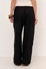 Pantalon de lino color marrón con costuras blancas decorativas a lo largo de las piernas y corte amplio.