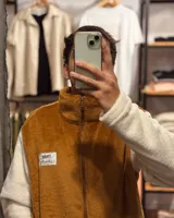 Campera marrón con mangas blancas de peluche con cierre frontal y cuello alto.