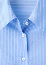 Camisa de manga larga con diseño a rayas en tonos celestes y blancos, cuello camisero y cierre frontal con botones.