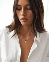 Collar de cristalitos facetados en tonos verdosos, con dije en forma de herradura dorada con detalles brillantes y cierre en acero.