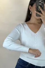 Buzo de hilo gris con textura acanalada, escote en V y cierre frontal con botones pequeños.