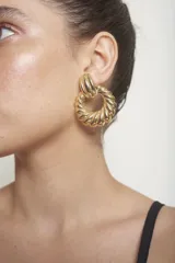 Aros dorados colgantes con diseño geométrico y ondas en relieve.
