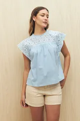 Blusa celeste de manga corta con broderie en el canesú y las mangas. Presenta cuello redondo con terminación de puntilla y recorte fruncido.