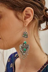 Aro colgante de estilo étnico con diseño de corazón calado, adornado con piedras turquesas y pequeños dijes colgantes en la parte inferior.
