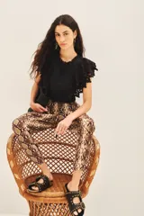 Pantalón estilo babucha con estampado de piel de serpiente en tonos marrones y beige. Posee cintura elástica con cordón de ajuste, puños ajustables en los tobillos y detalles metálicos.