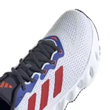 Championes de running Adidas modelo Switch Run, con parte superior de malla blanca, detalles en azul y las icónicas tres tiras en color rojo. Presentan una entresuela de EVA con diseño de rebajes para mayor amortiguación y suela exterior de goma negra.