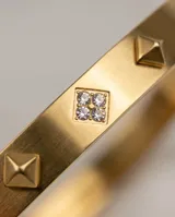 Esclava rígida de acero con baño de oro, decorada con tachuelas cuadradas y circonias incrustadas.