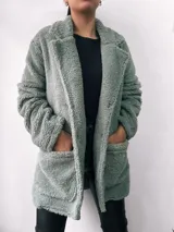 Saco verde de tela tipo teddy, con cuello solapa, corte oversize, mangas largas y bolsillos frontales.