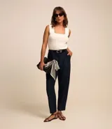 Pantalón de vestir estilo carrot, color azul marino oscuro, de tiro alto con trabillas y transpasse en la cintura. Presenta recortes delanteros con costura aparente (pespunte) y bolsillos.