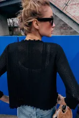Chaqueta de punto calado con diseño pointelle, cuello redondo y manga larga. Presenta cierre frontal con corchete oculto y terminaciones con detalle de ondas en puños y ruedo.