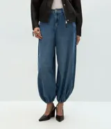Pantalón de jean estilo aladín con cintura alta, corte amplio y piernas voluminosas que se ajustan en el bajo con puño elástico. Cuenta con pretina con presillas, cierre tradicional y bolsillos funcionales.