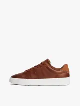 Zapatillas de estilo tenis Tommy Hilfiger confeccionadas en piel color marrón, con diseño de corte bajo, cordones al tono y suela de goma blanca. Presenta un panel de gamuza a contraste en el talón y el logo de la marca grabado en el lateral.