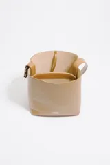 Bolso de hombro tipo cubo de estructura rígida, color marrón oscuro, confeccionado en piel vacuna. Posee asa regulable con hebilla metálica y cierre de cordón en la parte superior. Lleva el logo metálico de Bimba y Lola en la parte frontal inferior.