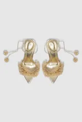 Sandalias de tacón alto doradas, con punta fina, tiras para atar al tobillo y empeine decorado con aplicaciones de cuentas y pedrería en relieve.