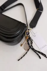 Cartera bandolera de tamaño compacto en color camel, con diseño estructurado y solapa frontal. Incluye doble asa: una corta fija de cuero sintético y una correa larga estilo sport regulable. Cuenta con cierre de cremallera y broche imantado, además de un detalle de llavero colgante.