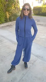 Conjunto de dos piezas compuesto por una campera de cuello alto con cierre frontal y mangas largas con orificios para pulgares, y un pantalón tipo babucha con cintura ajustable y puños elásticos en los tobillos. El diseño presenta una textura sutil en la tela.