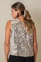 Blusa sin mangas confeccionada en tela cubierta de lentejuelas doradas y plateadas, con escote redondo y corte holgado.