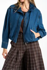 Campera bomber de jean azul con cierre frontal metálico, cuello alto y diseño oversize. Presenta costuras reforzadas y puños rectos.