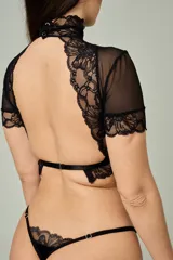 Conjunto de lencería negro compuesto por un top de cuello alto con mangas cortas de microtul y detalles de encaje, y una tanga regulable con aplique de encaje.
