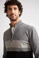 Sweater de tejido de punto con diseño color block en tonos gris, gris claro y negro. Presenta cuello levemente elevado con cierre frontal parcial, mangas largas con puños acanalados y logo bordado en el pecho.