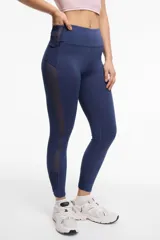 Calza deportiva larga color gris, con cintura alta, detalles de transparencias laterales en tul y bolsillos laterales.