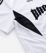 Remera de manga corta en tejido sintético color blanco, con cuello redondo y diseño de estilo deportivo. Presenta estampado frontal con lettering gótico y detalles laterales en tejido microperforado.