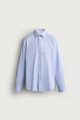 Camisa de corte slim fit en color celeste, confeccionada en tejido de fácil planchado. Presenta cuello italiano, manga larga con puños abotonados y cierre frontal con botones.
