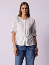 Blusa blanca de cuello redondo con apertura central y botones. Mangas 3/4 con detalle de bordado calado.