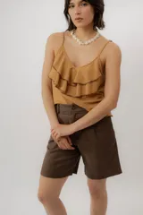 Musculosa negra con escote en V, breteles finos regulables y doble volado frontal con pespuntes.