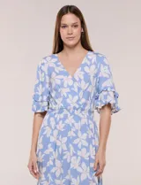 Vestido midi de calce holgado y caída fluida con escote en V cruzado, cintura elastizada fruncida y mangas cortas con volados superpuestos. Cuenta con un diseño estampado de flores grandes en tonos amarillo, blanco, azul marino y verde.